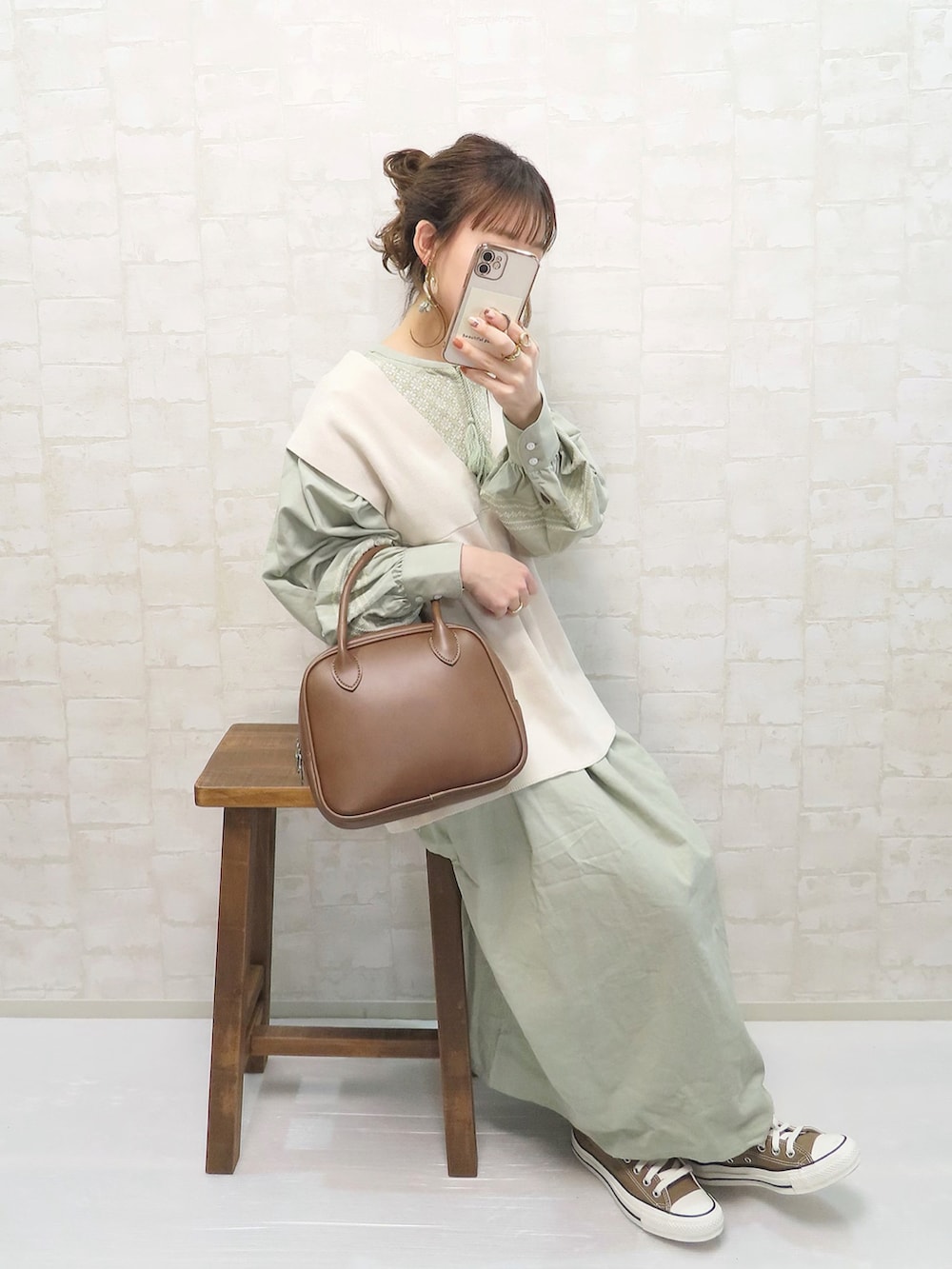 グリーン系のワンピース、ベージュ系のベスト、ブラウン系のショルダーバッグを着用したレディースの春コーディネートの2枚目の写真