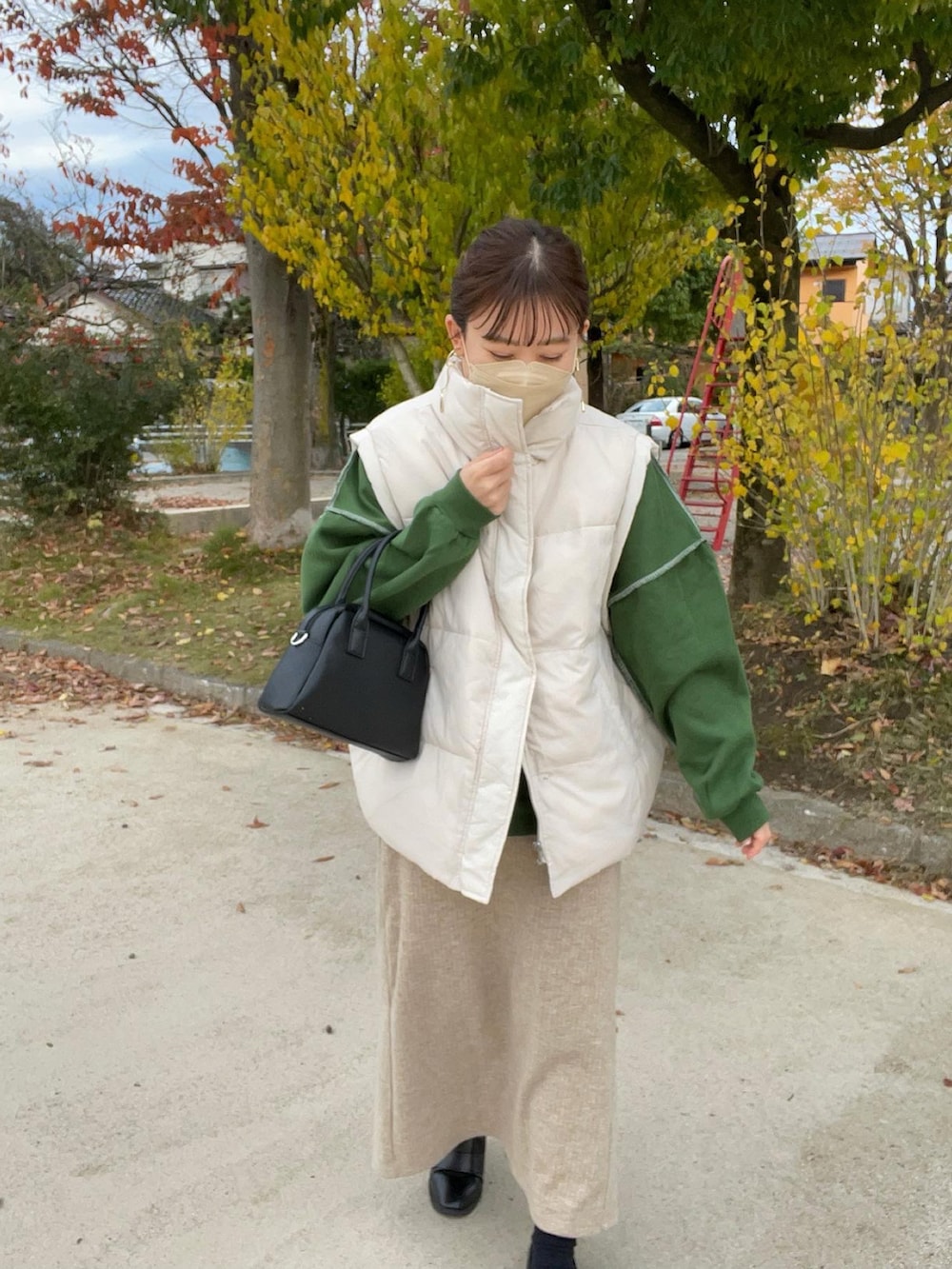 グリーン系のスウェット、ホワイト系のダウンベスト、ブラック系のボストンバッグを着用したレディースの秋コーディネートの5枚目の写真