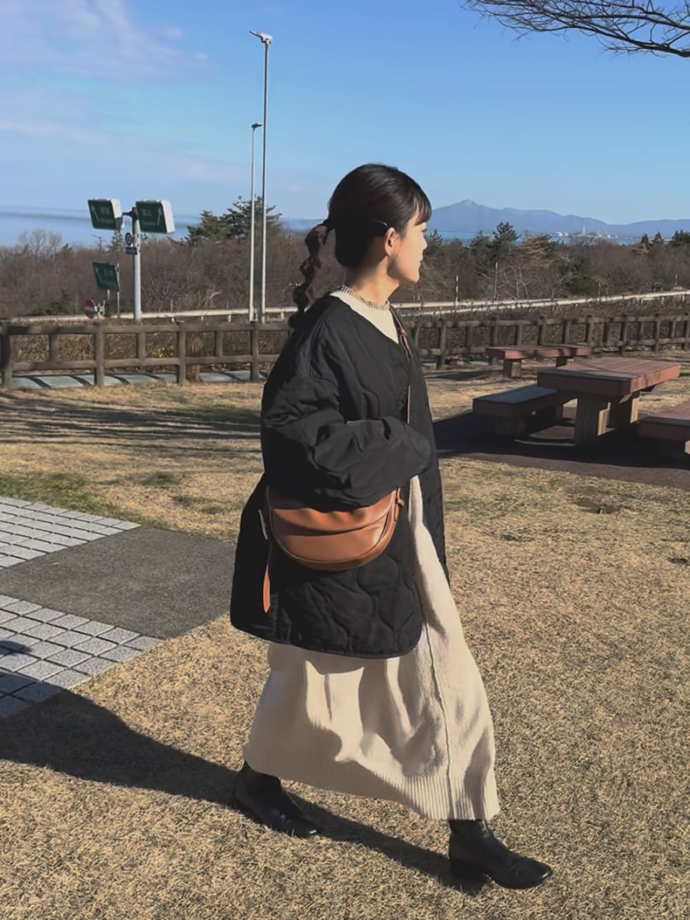 ブラック系のノーカラージャケット、ホワイト系のワンピース、ブラウン系のハンドバッグを着用したレディースの冬コーディネートの5枚目の写真