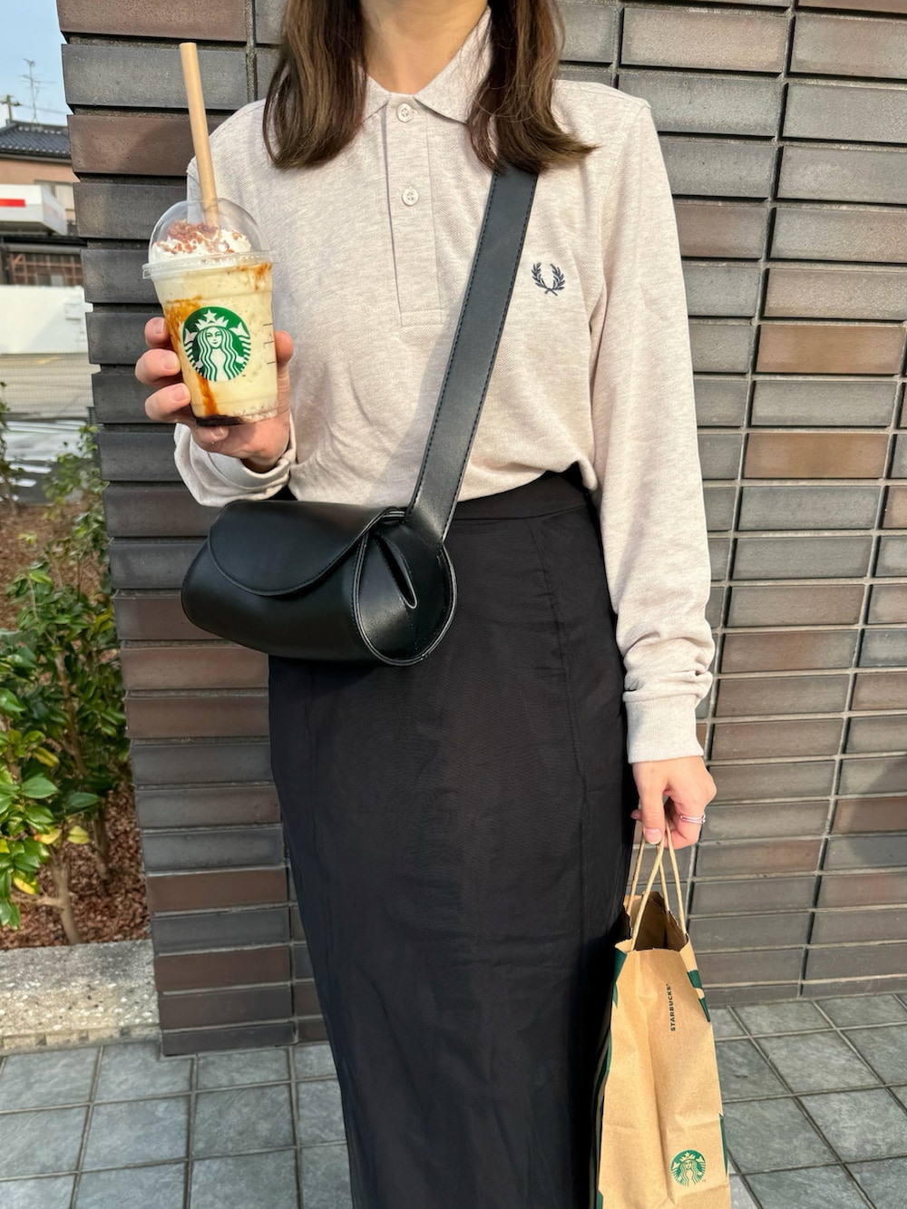ベージュ系のポロシャツ、ブラック系のスカート、ブラック系のショルダーバッグを着用したレディースの秋コーディネートの4枚目の写真