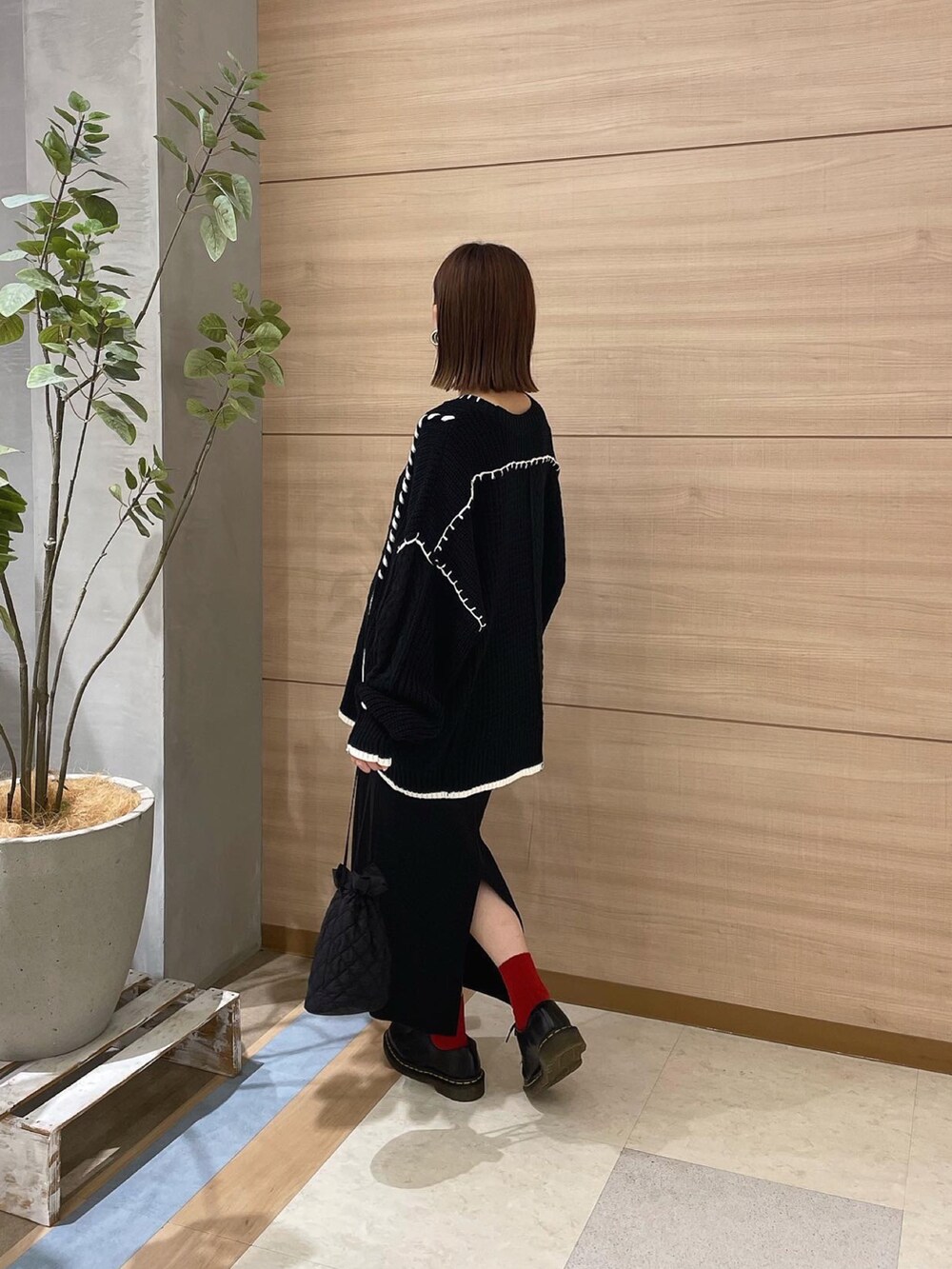 ブラック系のニット/セーター、ブラック系のショルダーバッグ、ブラック系のブーツを着用したレディースの秋コーディネートの4枚目の写真