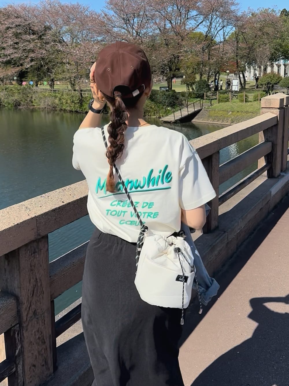 ホワイト系のTシャツ/カットソー、ブラック系のスカート、ベージュ系のスニーカーを着用したレディースの夏コーディネートの2枚目の写真
