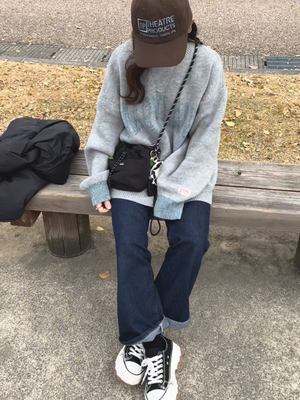 グレー系のニット/セーター、ブルー系のデニムパンツ、ブラック系のスニーカーを着用したレディースの冬コーディネートの2枚目の写真