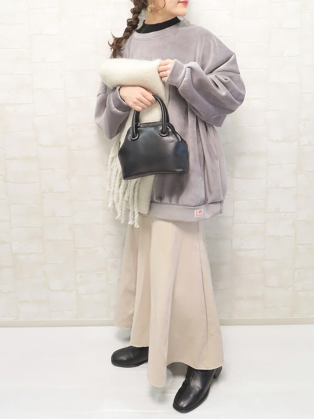 グレー系のスウェット、ブラック系のニット/セーター、ベージュ系のスカートを着用したレディースの冬コーディネートの2枚目の写真