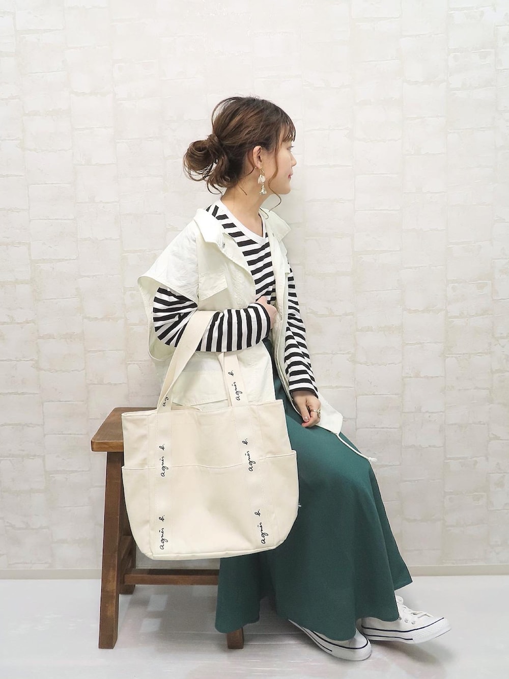 ブラック系のTシャツ/カットソー、ホワイト系のベスト、グリーン系のスカートを着用したレディースの春コーディネートの2枚目の写真