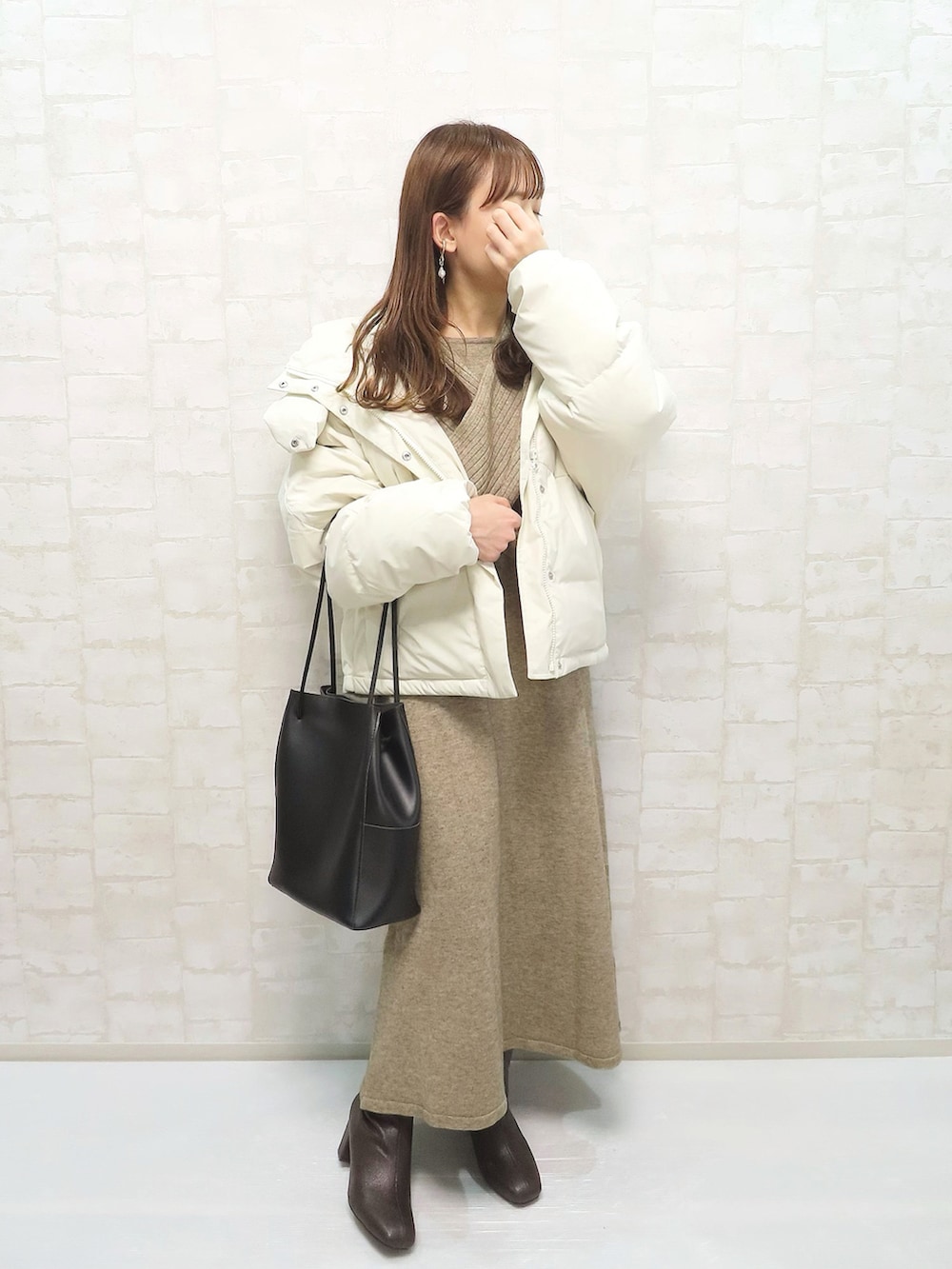 ベージュ系のダウンジャケット/コート、ベージュ系のワンピース、ブラウン系のブーツを着用したレディースの冬コーディネートの2枚目の写真