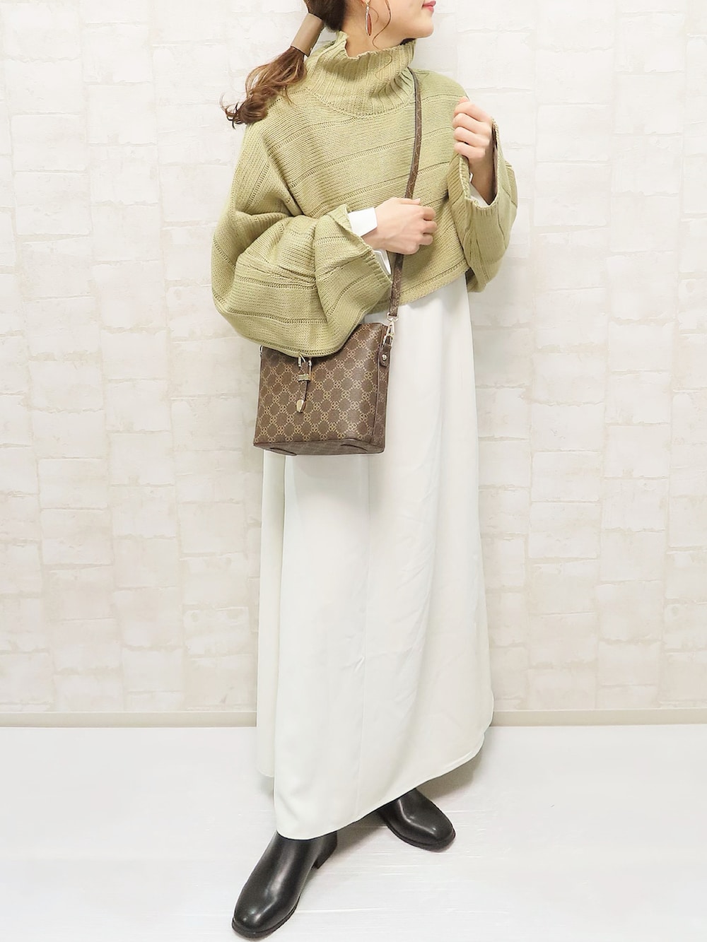 グリーン系のワンピース、ブラウン系のショルダーバッグ、ブラック系のブーツを着用したレディースの秋コーディネートの2枚目の写真