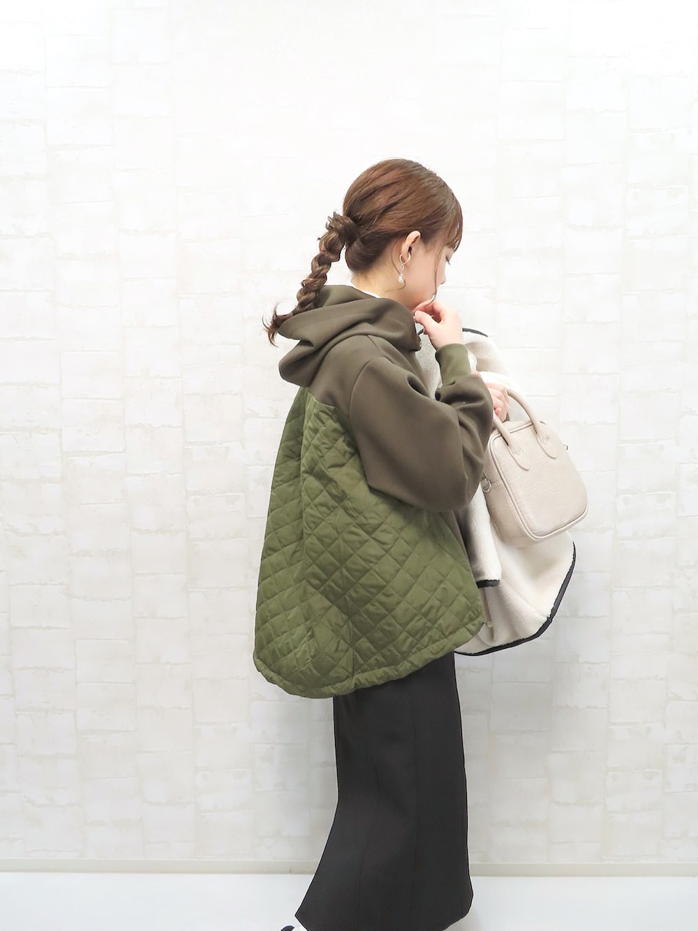 グリーン系のパーカー、ホワイト系のその他アウター、ベージュ系のショルダーバッグを着用したレディースの冬コーディネートの3枚目の写真