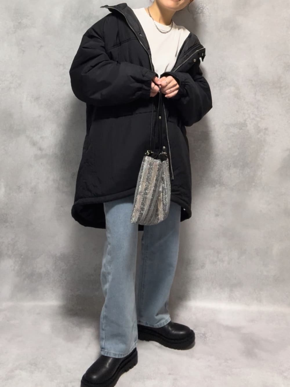 ブラック系のダウンジャケット/コート、ブルー系のデニムパンツ、ブラック系のブーツを着用したレディースの秋コーディネートの3枚目の写真