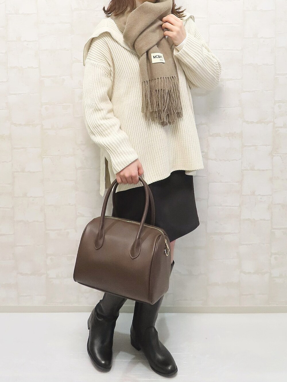 ホワイト系のニット/セーター、ブラック系のスカート、ブラック系のブーツを着用したレディースの冬コーディネートの3枚目の写真