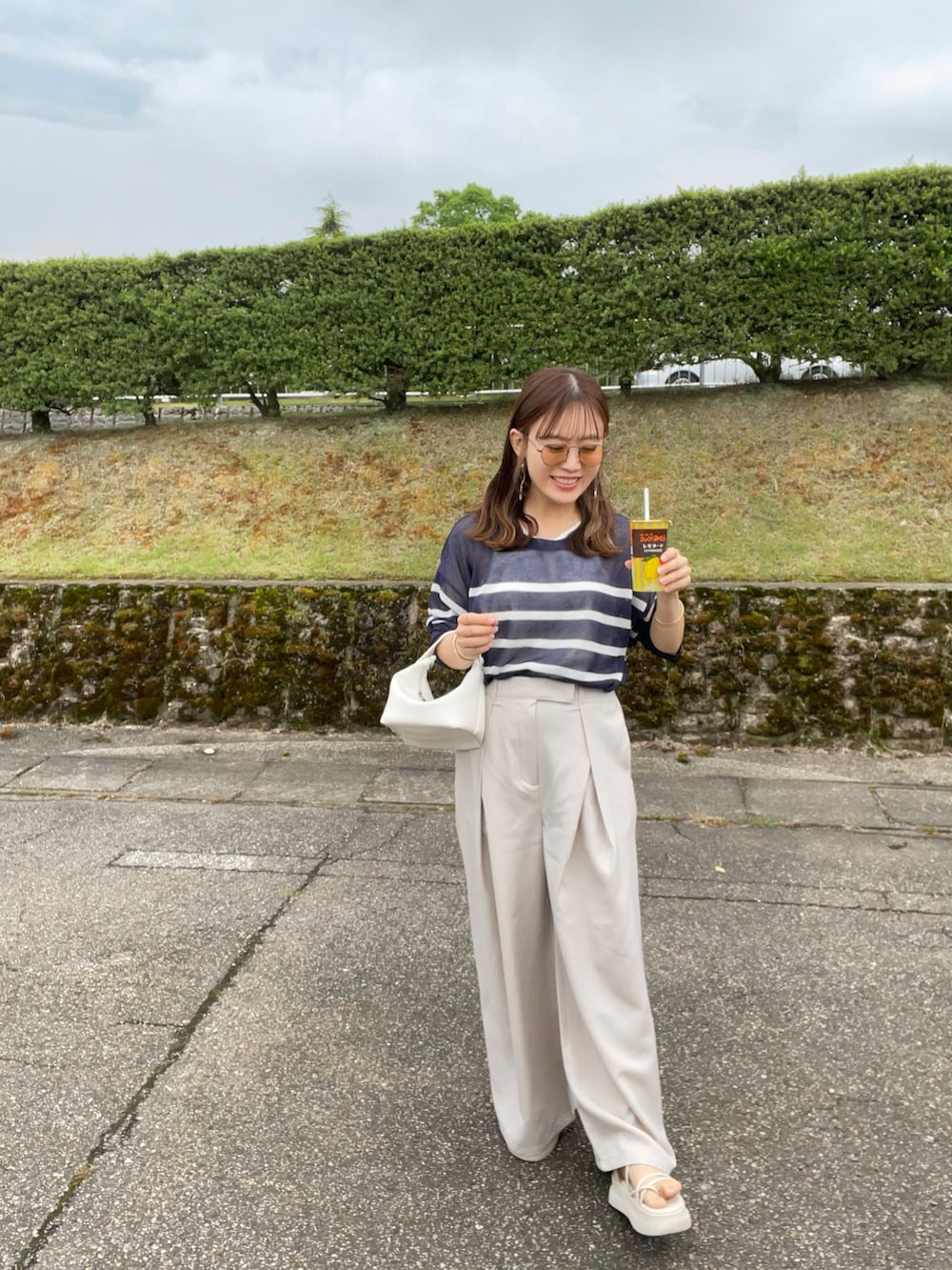 ブルー系のTシャツ/カットソー、ホワイト系のスラックス、ホワイト系のハンドバッグを着用したレディースの夏コーディネートの5枚目の写真