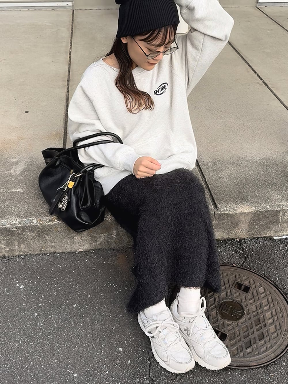 ベージュ系のスウェット、ホワイト系のスニーカー、ブラック系のスカートを着用したレディースの秋コーディネートの3枚目の写真