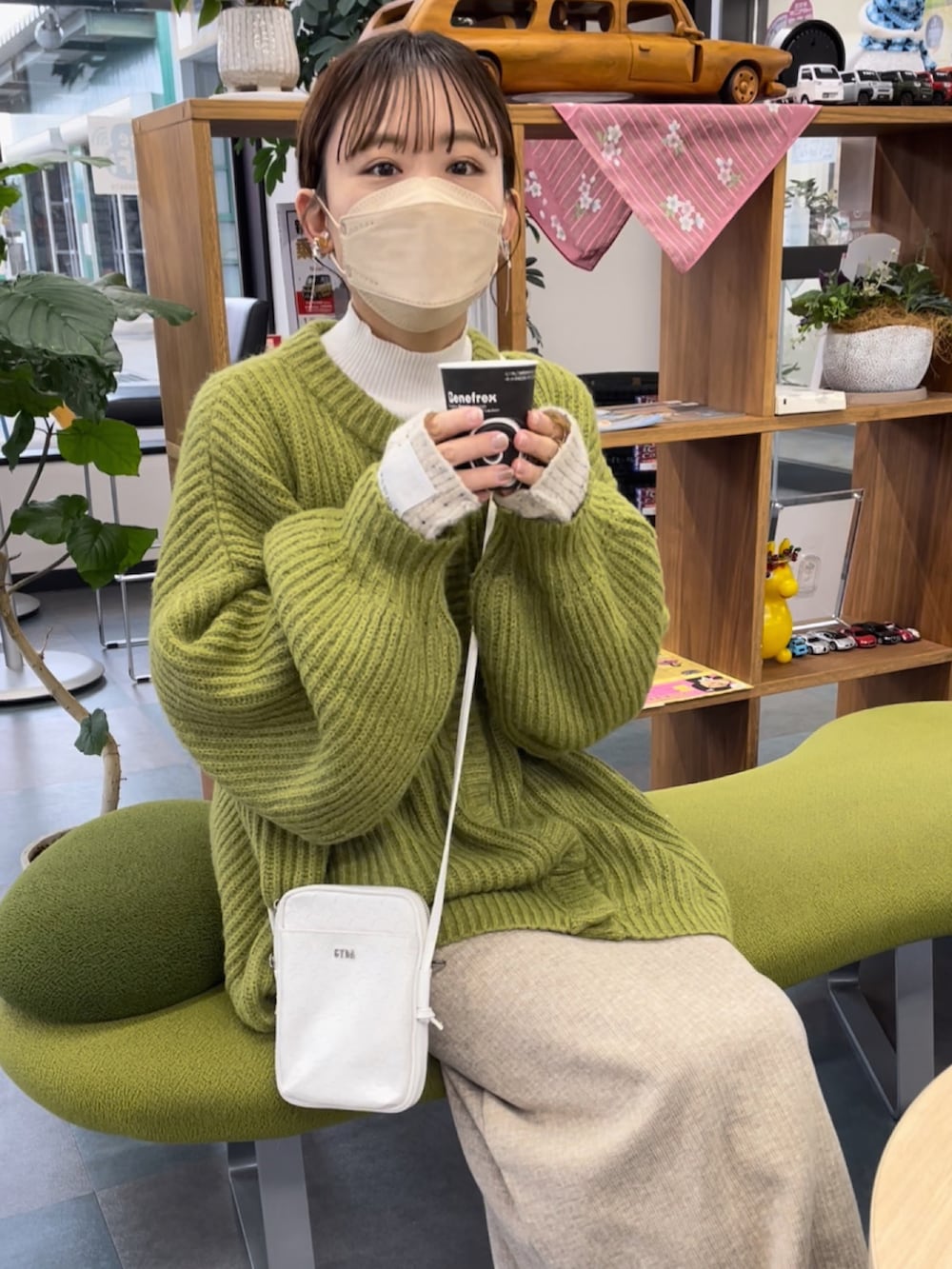 ホワイト系のショルダーバッグ、ホワイト系のニット/セーター、グリーン系のカーディガン/ボレロを着用したレディースの冬コーディネートの4枚目の写真