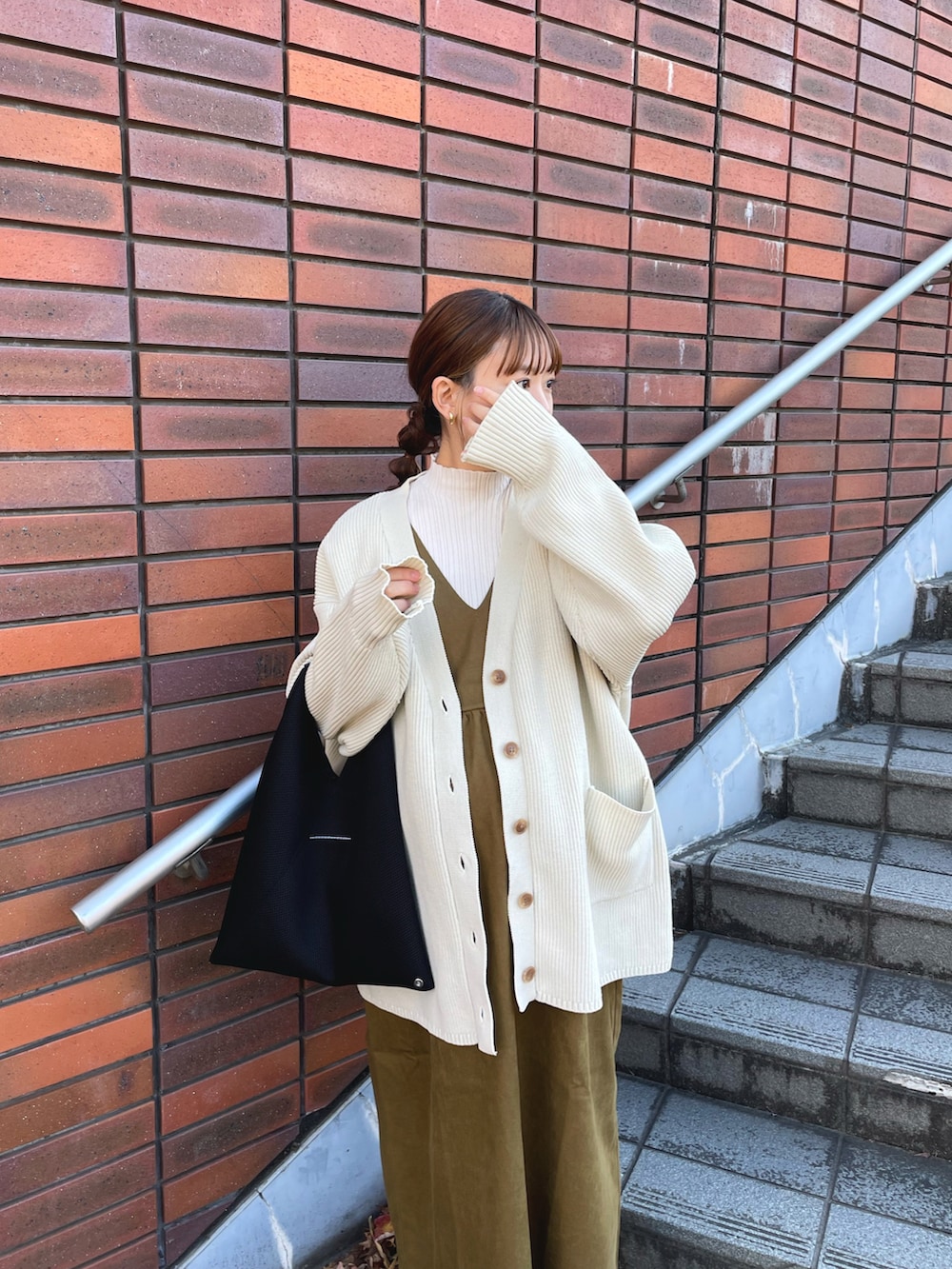 グリーン系のジャンパースカート、ホワイト系のニット/セーター、ホワイト系のカーディガン/ボレロを着用したレディースの冬コーディネートの3枚目の写真