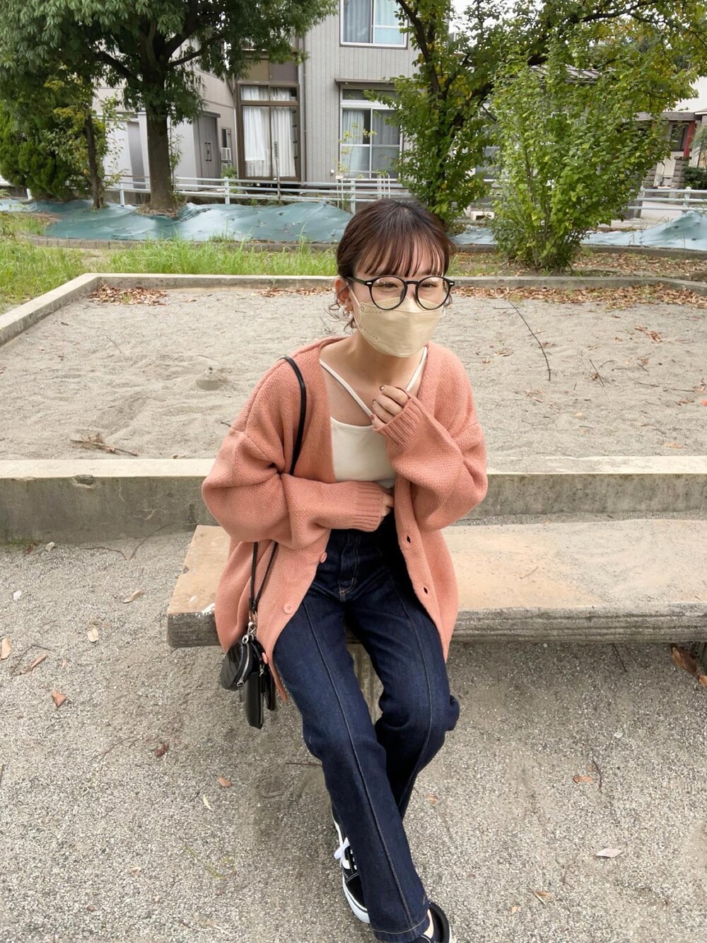 ピンク系のカーディガン/ボレロ、ホワイト系のキャミソール、ブラック系のデニムパンツを着用したレディースの秋コーディネートの3枚目の写真