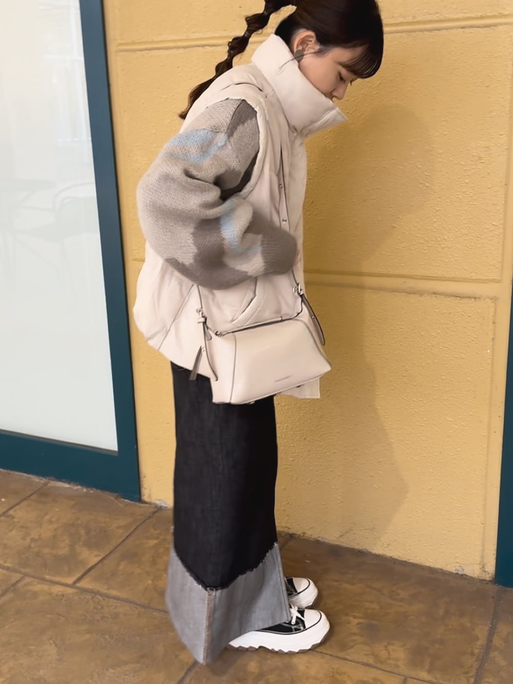 グレー系のニット/セーター、ブラック系のデニムスカート、ブラック系のトートバッグを着用したレディースの冬コーディネートの3枚目の写真