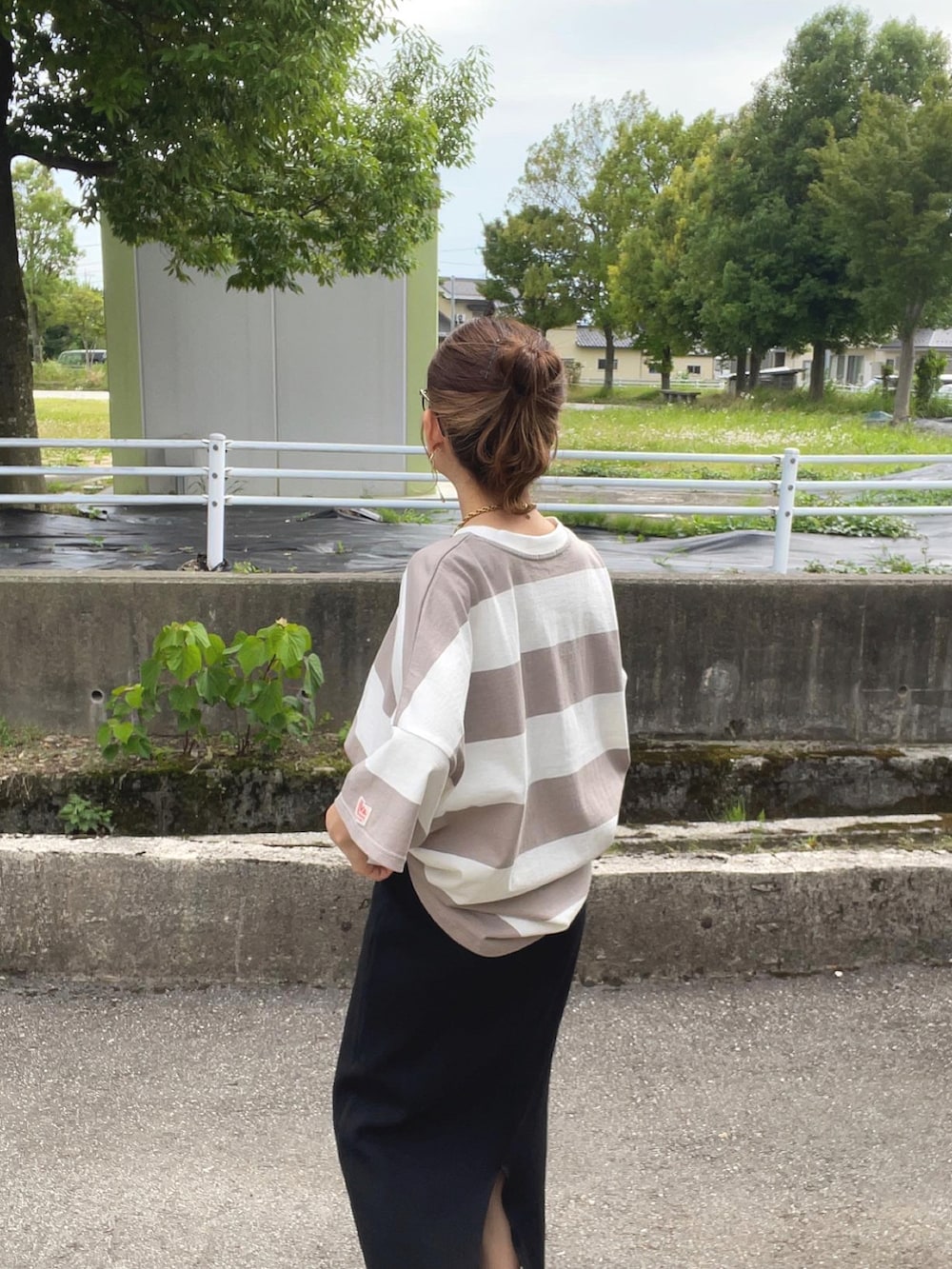 ベージュ系のTシャツ/カットソー、ブラック系のスカート、ホワイト系のハンドバッグを着用したレディースの夏コーディネートの3枚目の写真