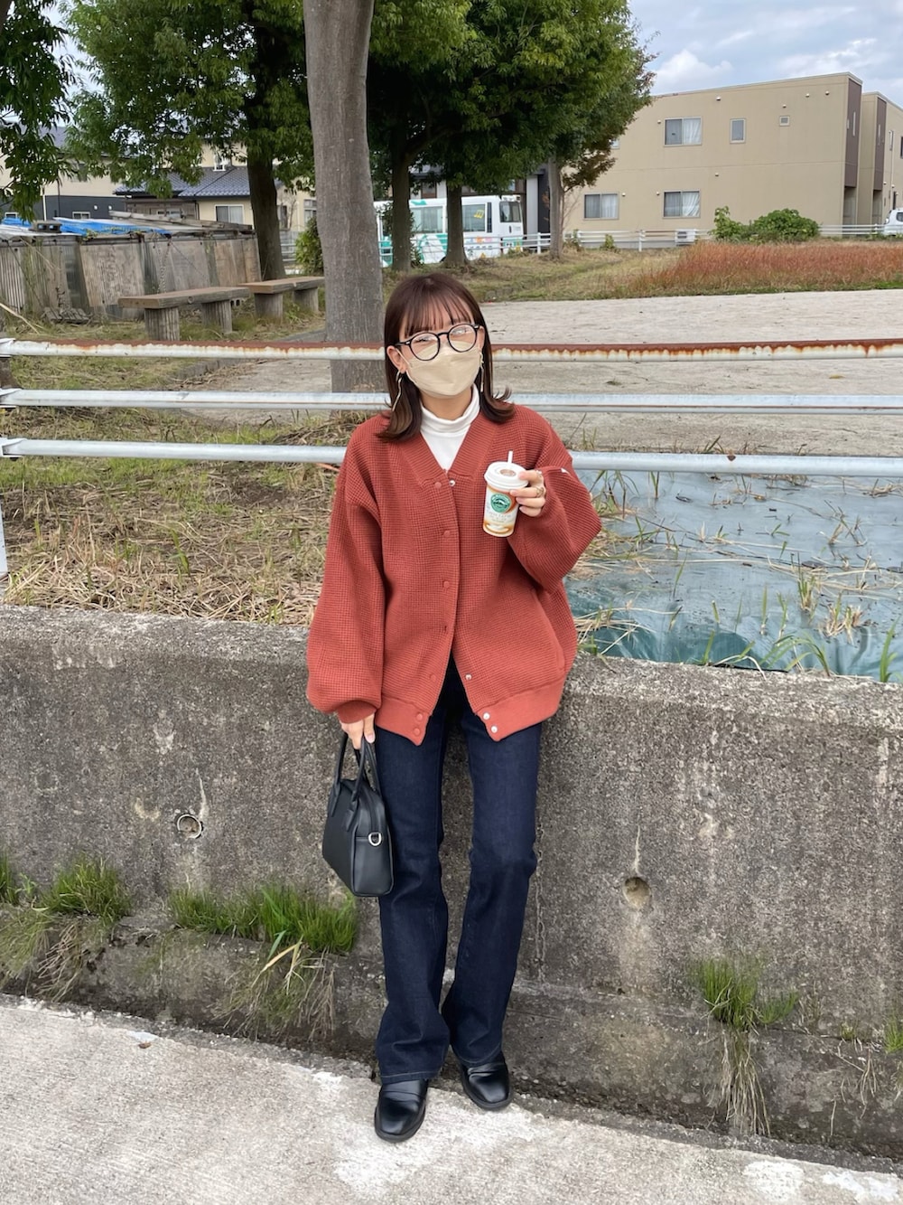 レッド系のカーディガン/ボレロ、ブルー系のデニムパンツ、ブラック系のボストンバッグを着用したレディースの秋コーディネートの4枚目の写真