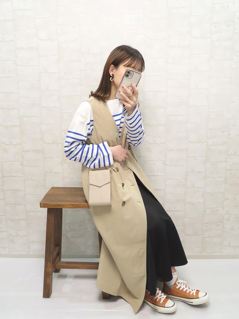 ベージュ系のトレンチコート、ブルー系のTシャツ/カットソー、ブラック系のスカートを着用したレディースの春コーディネートの2枚目の写真