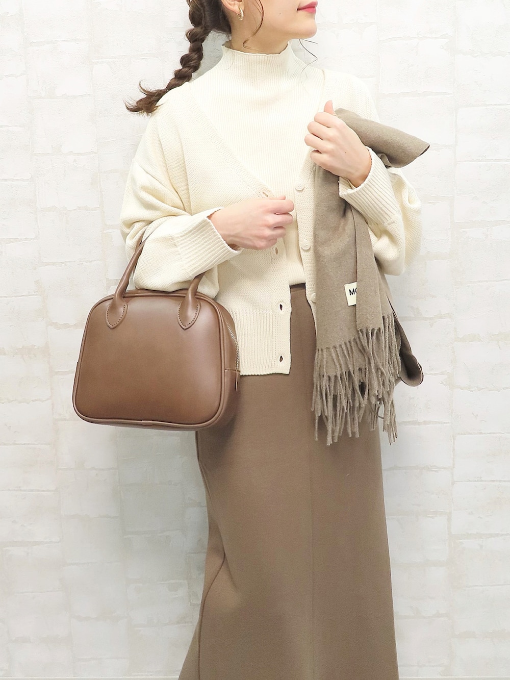 ホワイト系のカーディガン/ボレロ、ホワイト系のニット/セーター、ブラウン系のスカートを着用したレディースの冬コーディネートの3枚目の写真