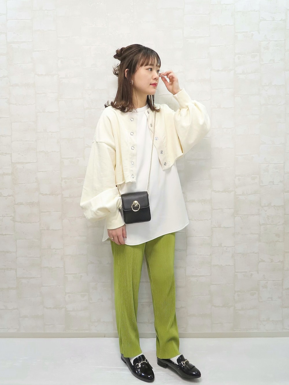 ホワイト系のスウェット、グリーン系のパンツ、ブラック系のショルダーバッグを着用したレディースの春コーディネートの2枚目の写真