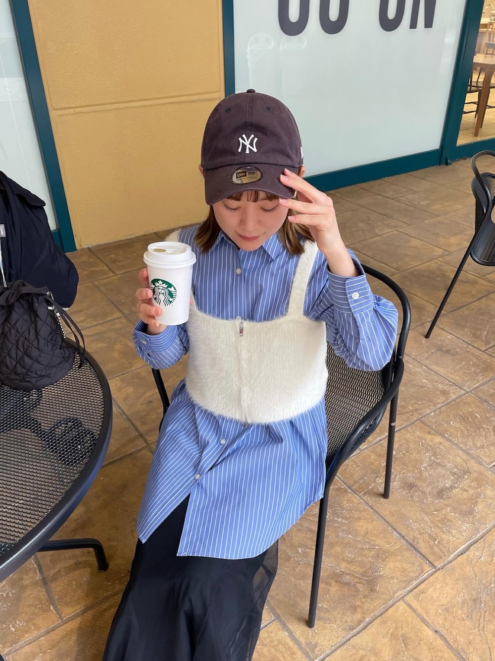 ブルー系のシャツ/ブラウス、ホワイト系のベスト、ブラック系のスカートを着用したレディースの春コーディネートの5枚目の写真