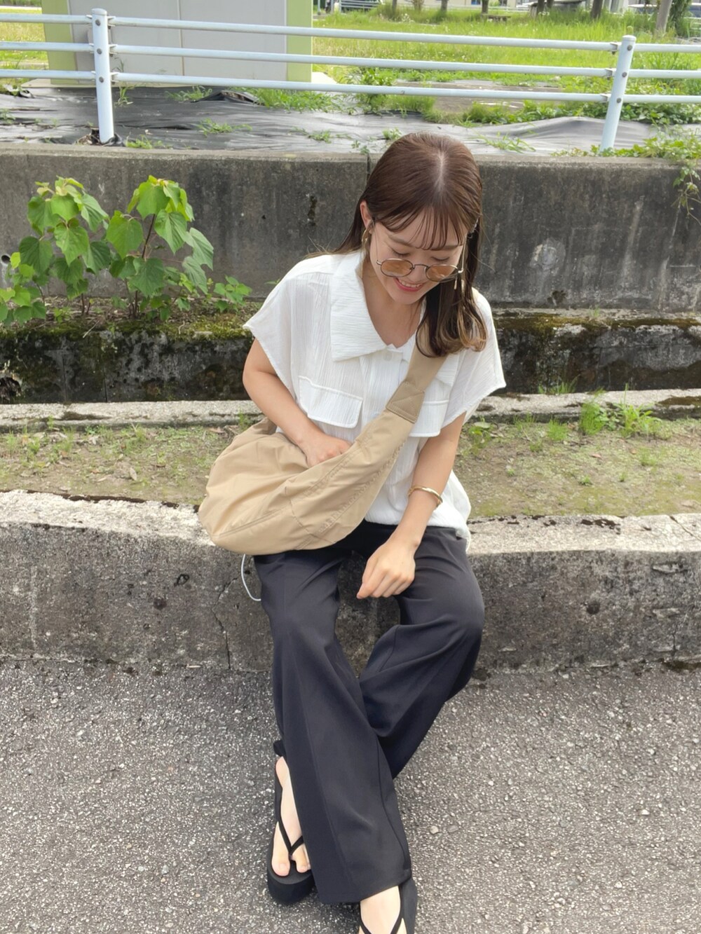ベージュ系のショルダーバッグ、ブラック系のパンツ、ブラック系のサンダルを着用したレディースの夏コーディネートの5枚目の写真