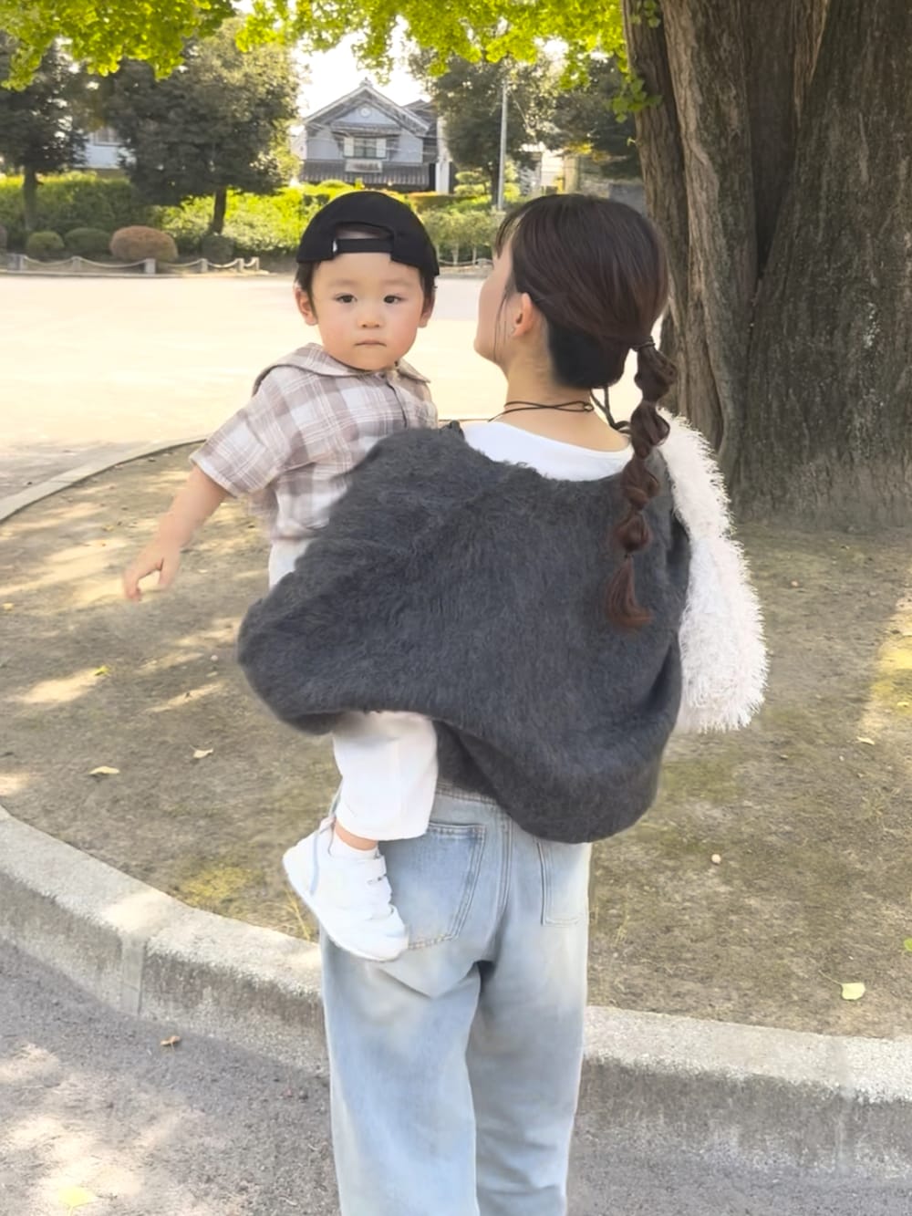 グレー系のカーディガン/ボレロ、ブルー系のデニムパンツ、ホワイト系のバッグを着用したレディースの秋コーディネートの4枚目の写真