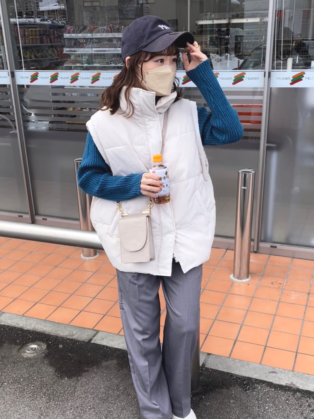 グレー系のパンツ、ブルー系のニット/セーター、ホワイト系のダウンベストを着用したレディースの冬コーディネートの4枚目の写真