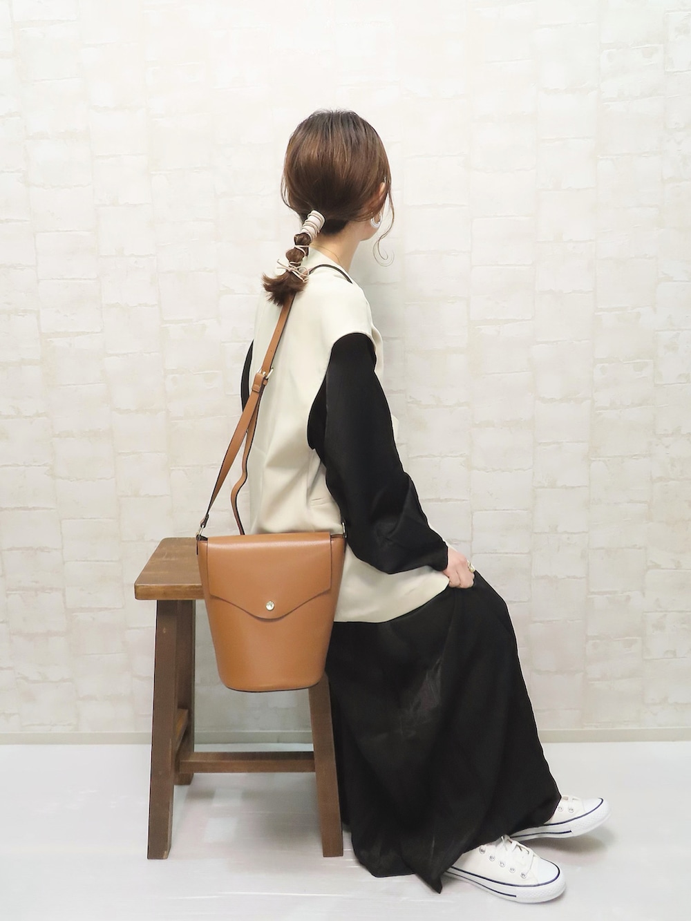 ブラック系のワンピース、ホワイト系のベスト、ホワイト系のスニーカーを着用したレディースの春コーディネートの2枚目の写真