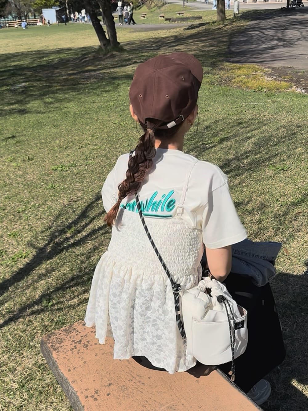 ホワイト系のTシャツ/カットソー、ブラック系のスカート、ベージュ系のスニーカーを着用したレディースの夏コーディネートの4枚目の写真
