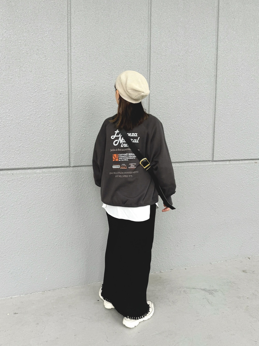 グレー系のスウェット、ブラック系のスカート、ブラック系のショルダーバッグを着用したレディースの秋コーディネートの2枚目の写真