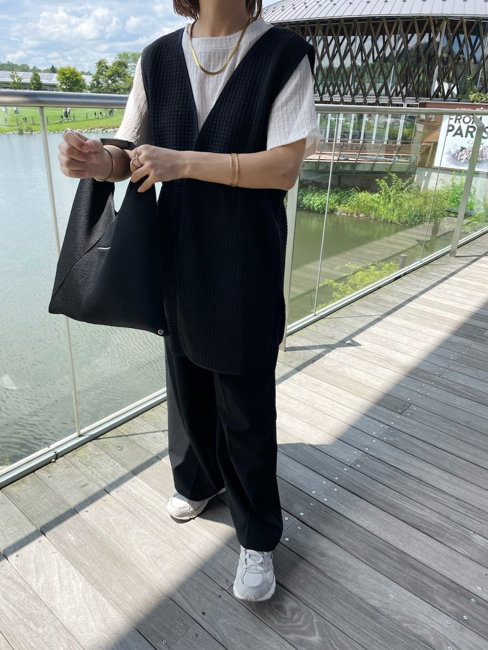 ブラック系のベスト、ホワイト系のTシャツ/カットソー、ブラック系のパンツを着用したレディースの夏コーディネートの2枚目の写真