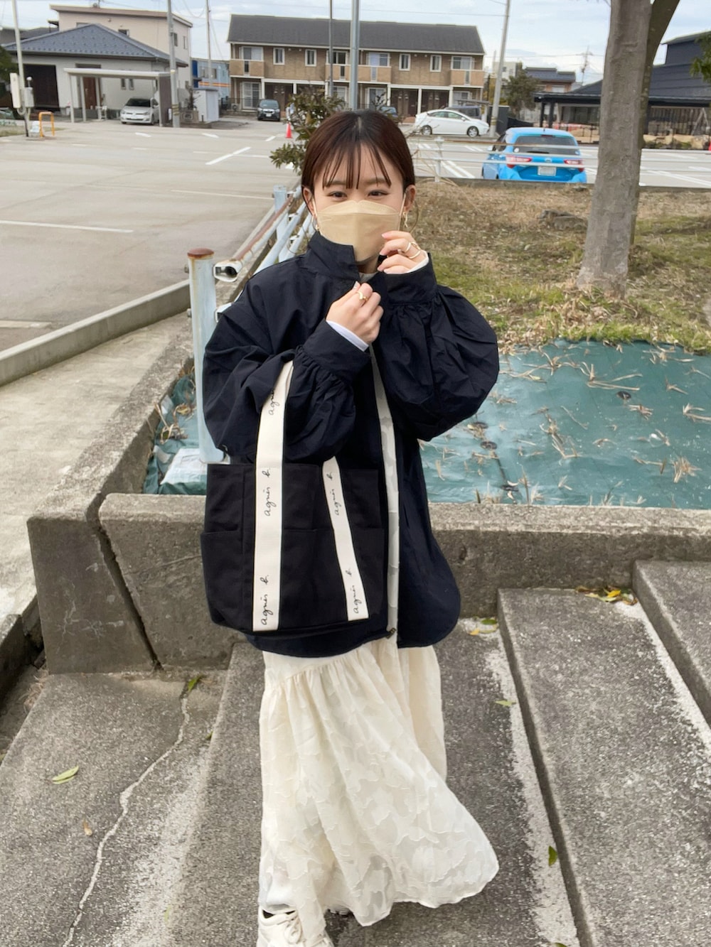 ホワイト系のドレス、ブラック系のトートバッグ、ブラック系のマウンテンパーカーを着用したレディースの冬コーディネートの2枚目の写真