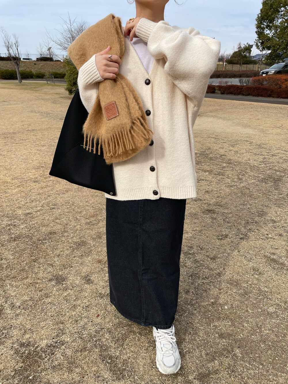 ホワイト系のカーディガン/ボレロ、ブラック系のデニムスカート、ブラック系のトートバッグを着用したレディースの冬コーディネートの4枚目の写真