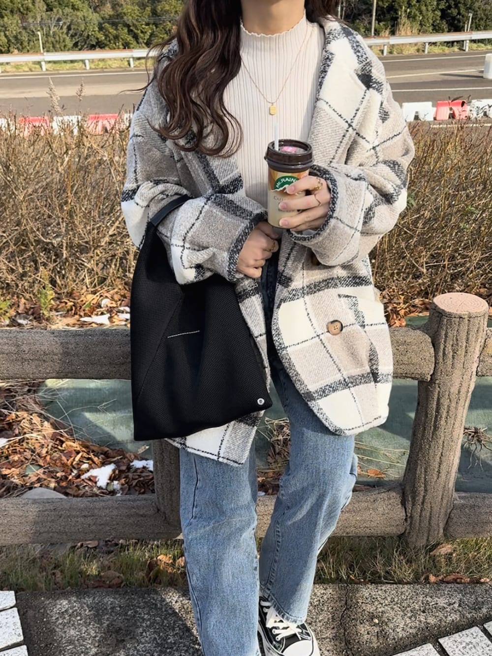 ホワイト系のチェスターコート、ブラック系のスニーカー、ブラック系のトートバッグを着用したレディースの冬コーディネートの2枚目の写真