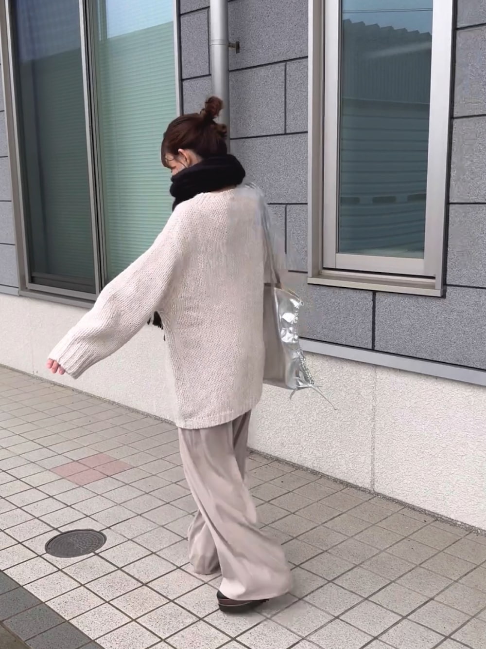 シルバー系のトートバッグ、ホワイト系のニット/セーター、ホワイト系のパンツを着用したレディースの冬コーディネートの3枚目の写真