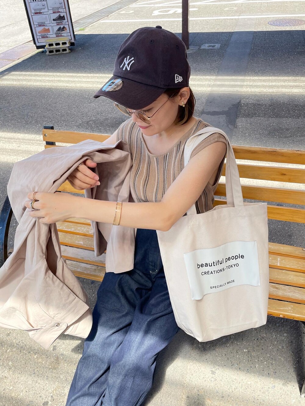 ベージュ系のタンクトップ、ブルー系のデニムパンツ、ホワイト系のトートバッグを着用したレディースの夏コーディネートの2枚目の写真