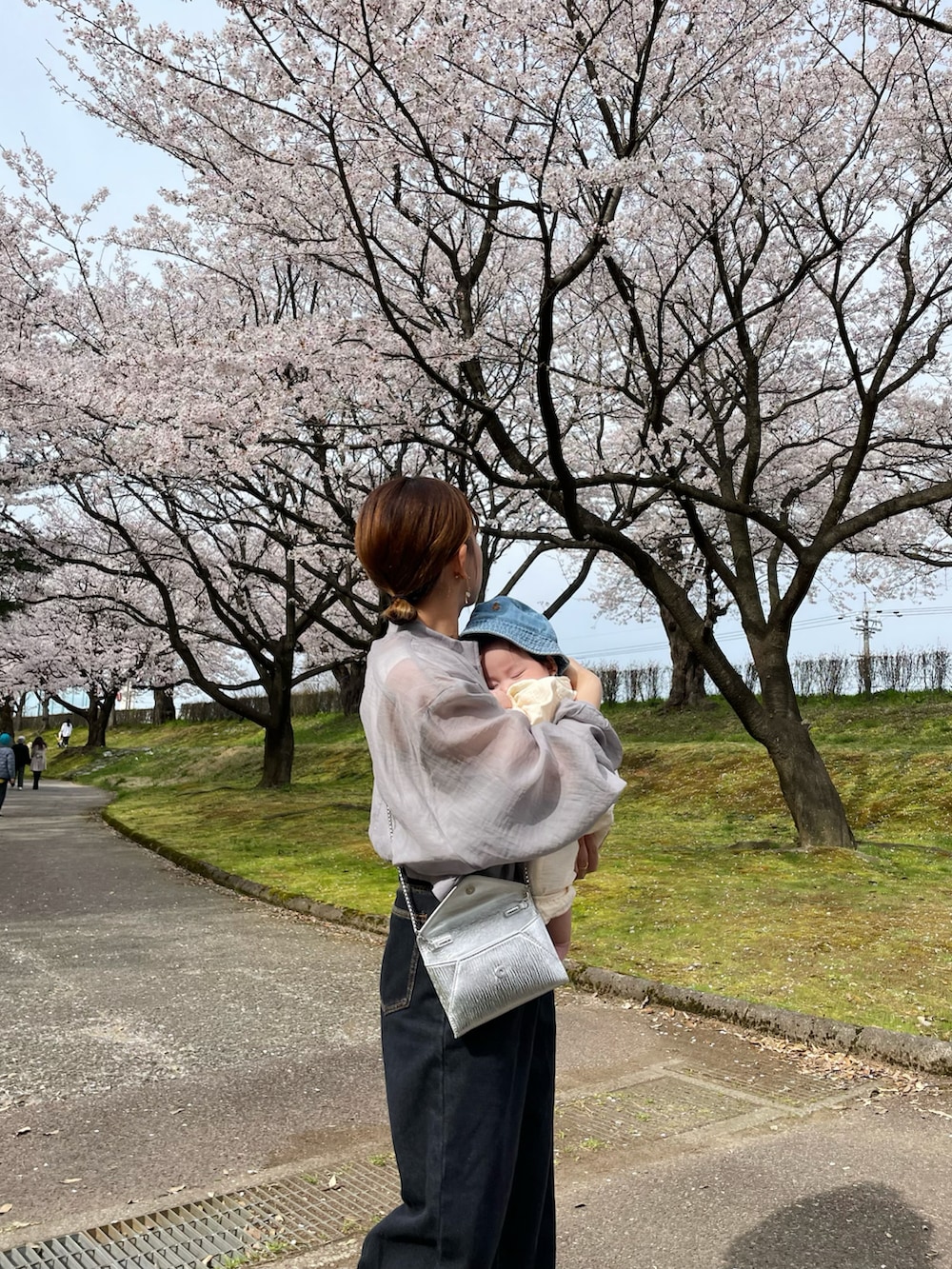 グレー系のブルゾン、ブラック系のデニムパンツ、ホワイト系のシューズを着用したレディースの春コーディネートの3枚目の写真