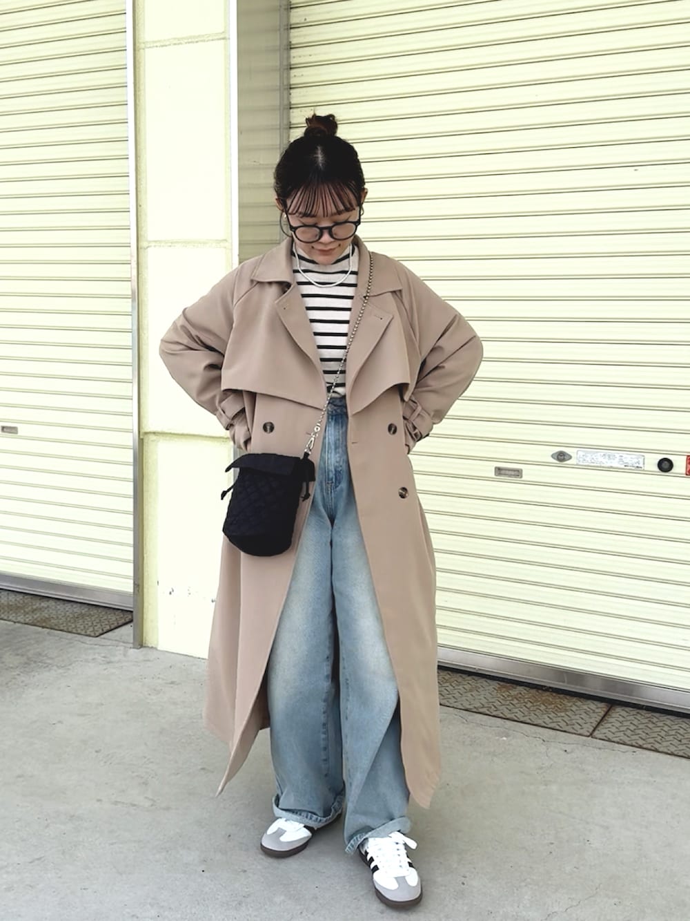 イエロー系のトレンチコート、グレー系のニット/セーター、ブルー系のデニムパンツを着用したレディースの冬コーディネートの3枚目の写真