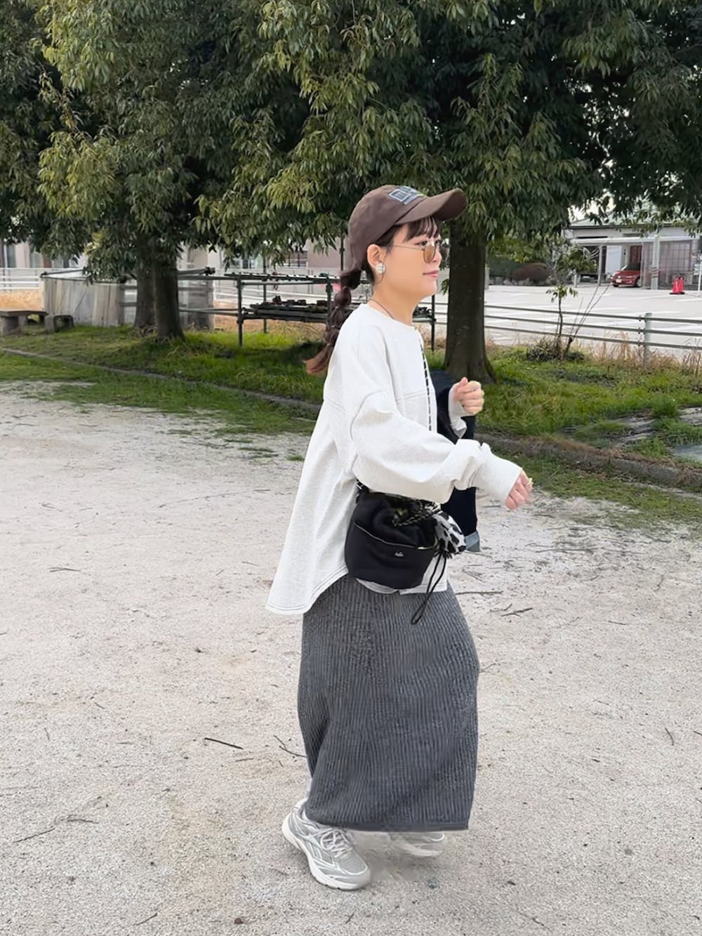ベージュ系のTシャツ/カットソー、ベージュ系のスニーカー、グレー系のスカートを着用したレディースの春コーディネートの4枚目の写真