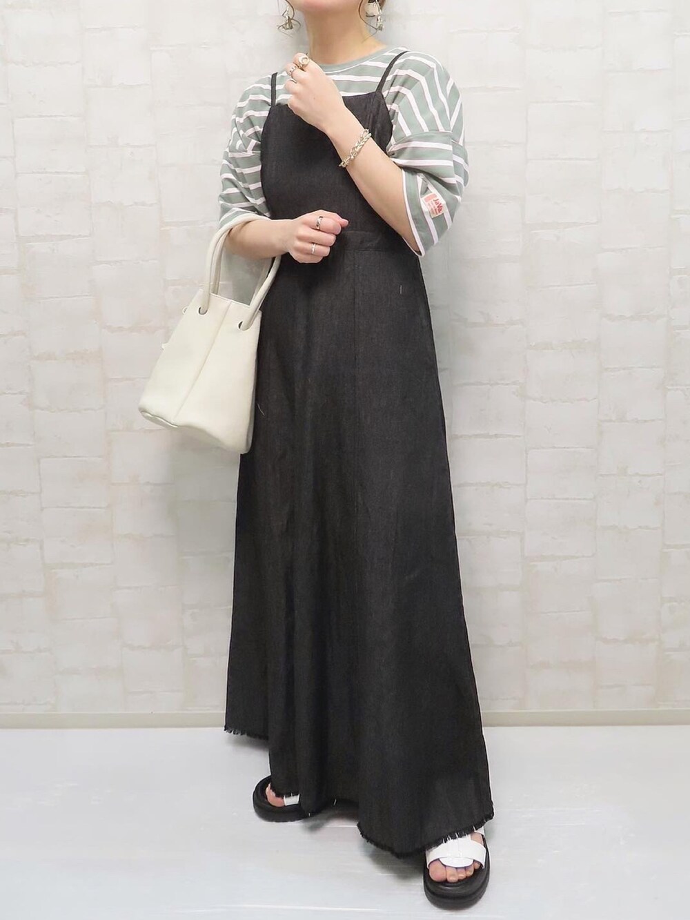 グリーン系のTシャツ/カットソー、ブラック系のワンピース、ホワイト系のハンドバッグを着用したレディースの春コーディネートの3枚目の写真