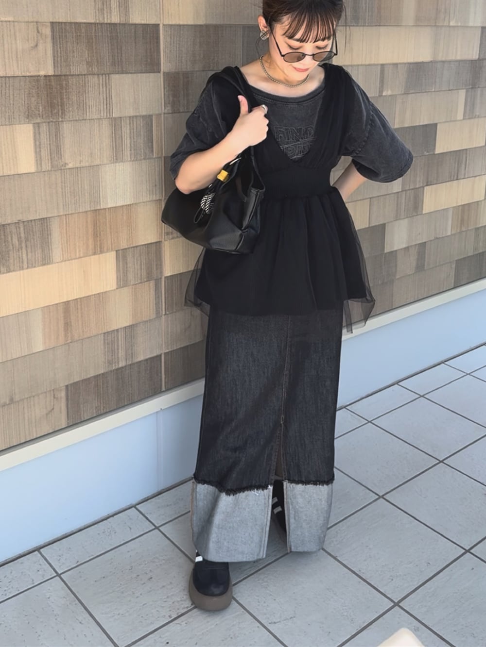 ブラック系のデニムスカート、グレー系のTシャツ/カットソー、ブラック系のベストを着用したレディースの秋コーディネートの2枚目の写真