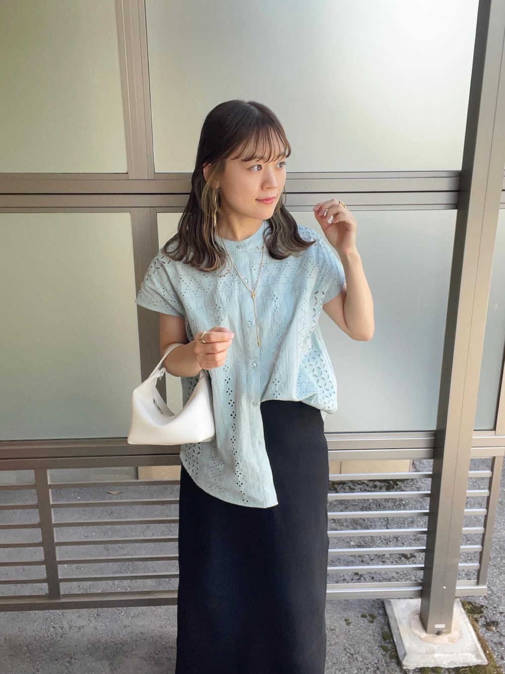 グリーン系のシャツ/ブラウス、ブラック系のスカート、ホワイト系のハンドバッグを着用したレディースの春コーディネートの5枚目の写真