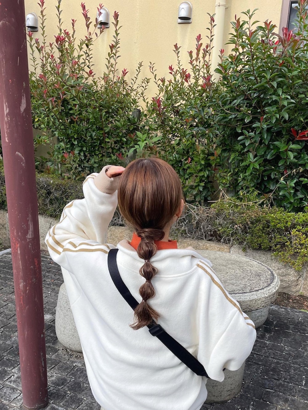 ホワイト系のスウェット、ブラウン系のニット/セーター、ブラック系のショルダーバッグを着用したレディースの秋コーディネートの2枚目の写真