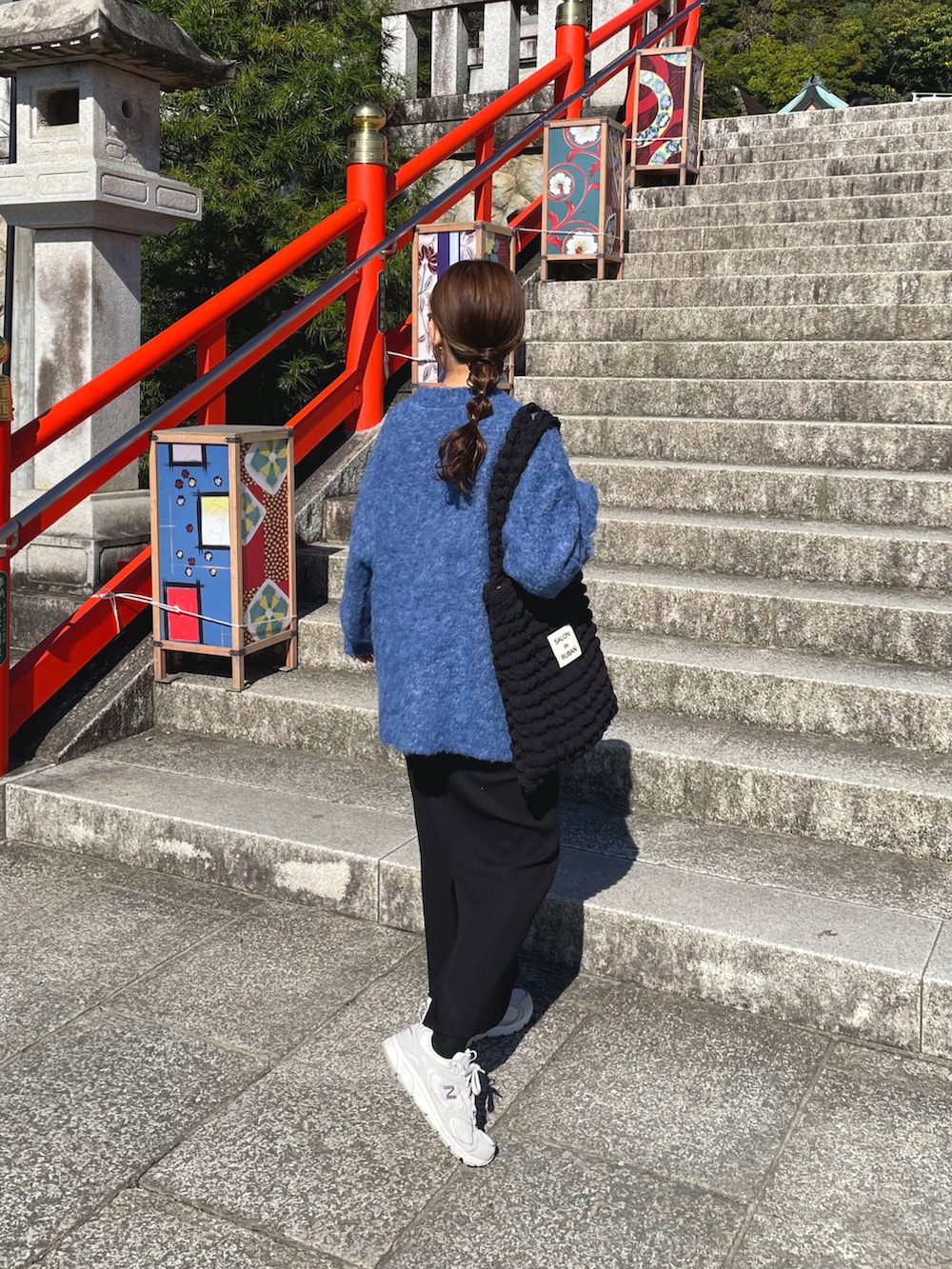 ブルー系のニット/セーター、ブラック系のトートバッグ、ホワイト系のスニーカーを着用したレディースの秋コーディネートの2枚目の写真