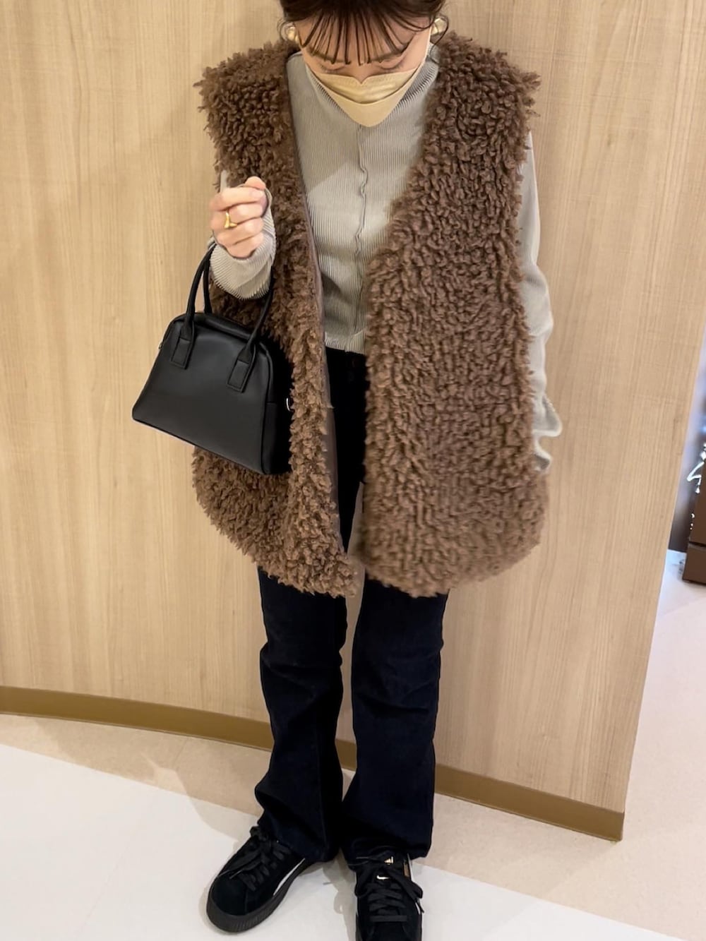 ブラウン系のベスト、ホワイト系のニット/セーター、ベージュ系のスカートを着用したレディースの冬コーディネートの3枚目の写真