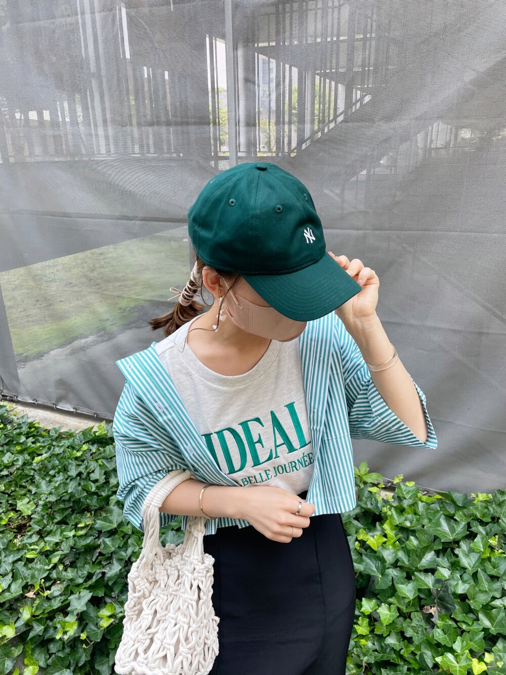 グリーン系のシャツ/ブラウス、ブラック系のスカート、ホワイト系のハンドバッグを着用したレディースの夏コーディネートの5枚目の写真