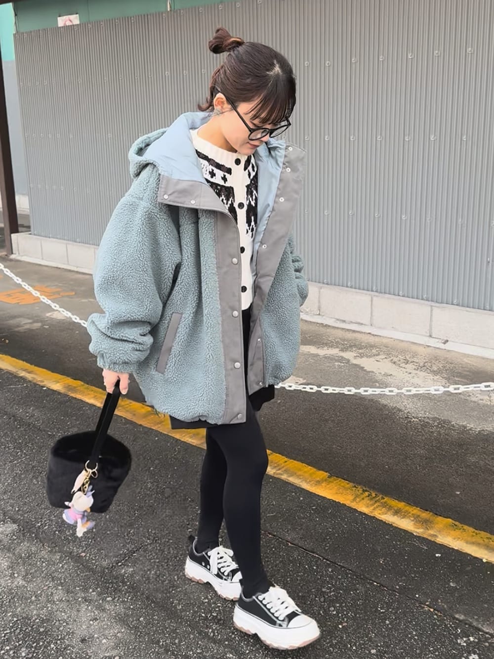 ブルー系のブルゾン、ブラック系のスラックス、ホワイト系のカーディガン/ボレロを着用したレディースの冬コーディネートの2枚目の写真