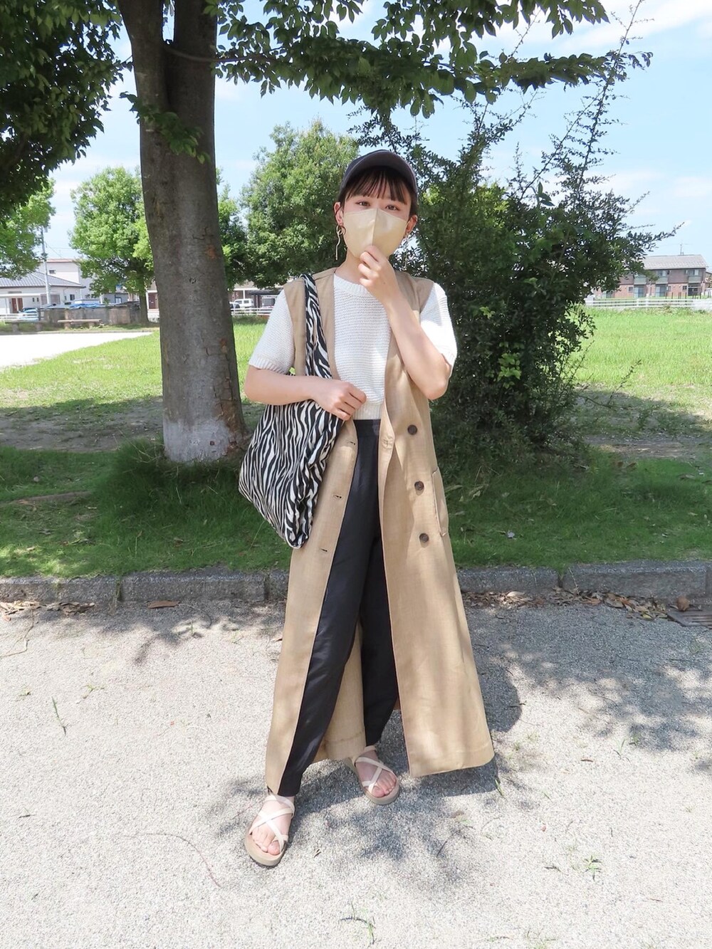 ベージュ系のベスト、ホワイト系のニット/セーター、ブラック系のその他パンツを着用したレディースの夏コーディネートの4枚目の写真